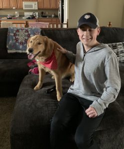 Ethan Edwards sitting on a couch at home with his dog. 