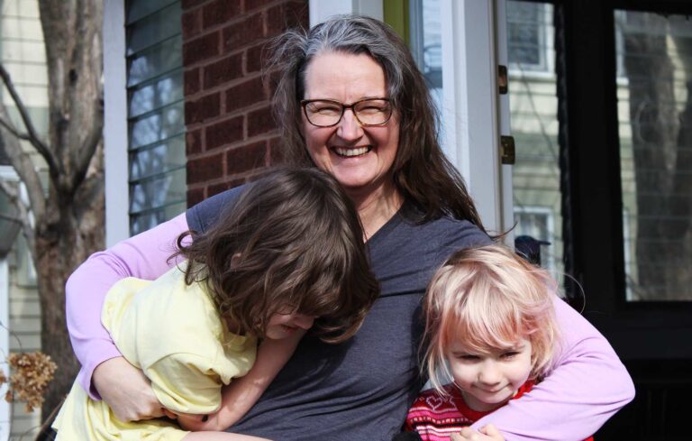 A family stands in front of a brick house.