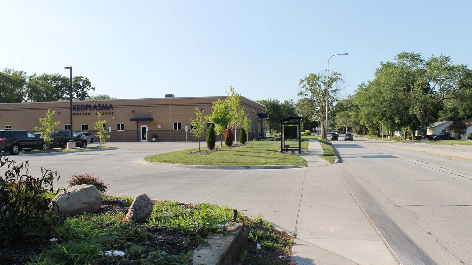 A one-story building with a sign that says "KEDPLASMA UNITED STATES" sits next to a parking lot and manicured grass.