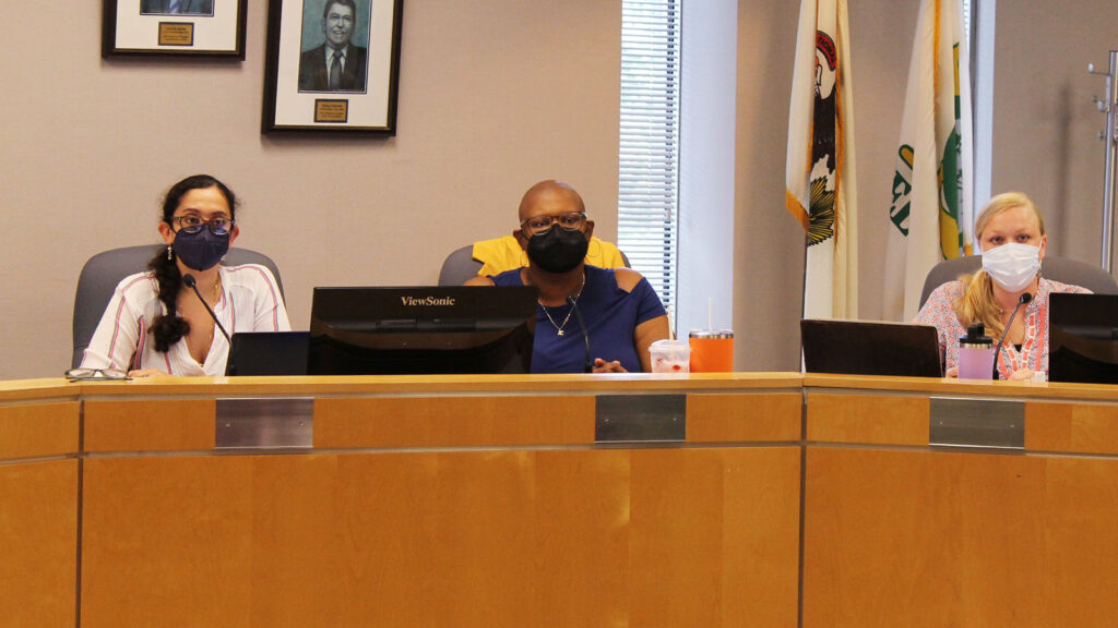 Three women sit behind a dias on July 11, 2022.