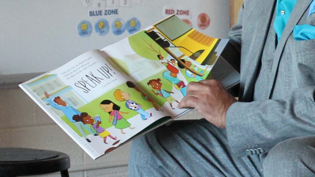 A man reads the book "Speak Up" during a class storytime.